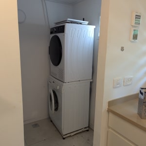 מכונת כביסה ומייבש כביסה מוערמים בחדר כביסה קטן