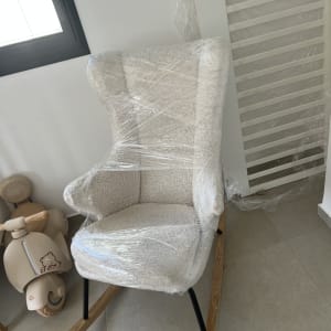 כיסא עטוף בניילון ליד חלון וצעצוע
