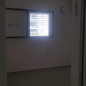 חדר ריק עם קירות צבועים בלבן וחלון קטן