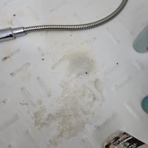 צינור מתכת גמיש על רצפת מקלחת מלוכלכת