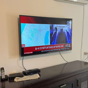 טלוויזיה על קיר עם מזגן ושלטים על שידה