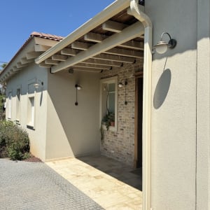 מרזב מחובר לגג רעפים עם קורות עץ חשופות