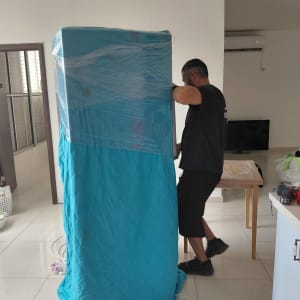 אדם עוטף רהיט בכיסוי כחול בבית