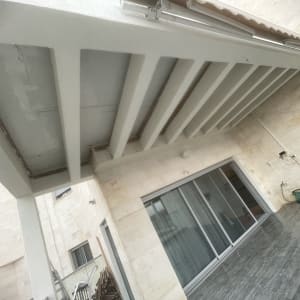 פרגולה מותקנת מעל מרפסת עם דלתות זכוכית