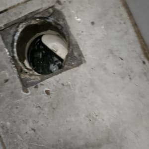 פתח ניקוז עם מכסה פלסטיק שבור ברצפה