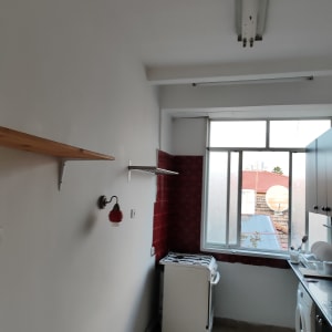 קיר צבוע בלבן עם מדף עץ ומנורה אדומה