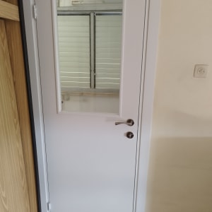 דלת לבנה עם חלון קטן וידית מתכת