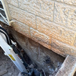 חפירה ליד קיר אבן עם כלי עבודה