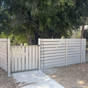 גדר עץ לבנה עם שער מתכת בגינה