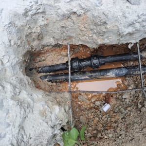 צינורות שחורים עם מחבר בתוך חפירה באדמה