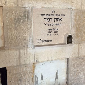 מצבה עם כיתוב בעברית על קיר אבן