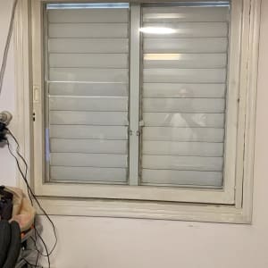 חלון עם תריסים סגורים ומכשיר מיזוג אוויר