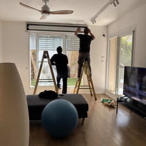 שני אנשים מתקינים תריסי אלומיניום בחלון גדול