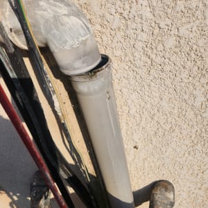 צינור פלסטיק אפור עם חיבור זוויתי על קיר