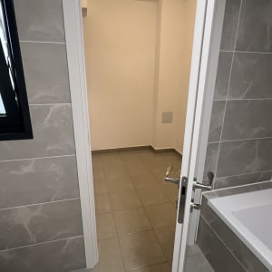 חדר אמבטיה נקי עם רצפה רטובה ודלת פתוחה
