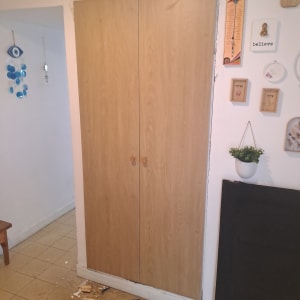 ארון עץ בנוי בנישה עם דלתות ציר בכניסה לבית