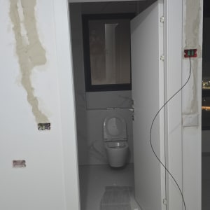 חוטי חשמל חשופים בקיר, דלי עם טיח על הרצפה