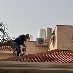 אדם עובד על גג רעפים עם כלי עבודה