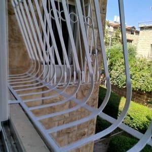 סורגי חלון לבנים על קיר אבן