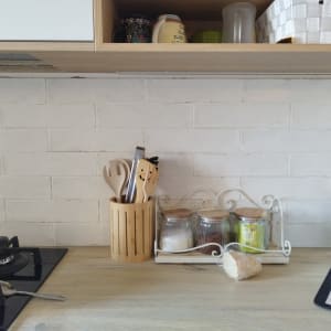 מטבח עם קיר לבנים לבן, כיריים וכלי מטבח