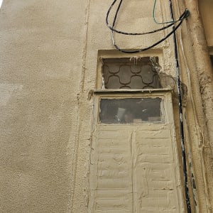 קיר חיצוני עם חלון וחוטי חשמל גלויים