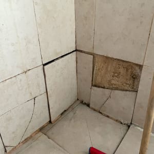 אריחים שבורים בקיר ורצפה, מטאטא אדום