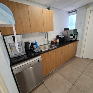 מטבח עם ארונות עץ, כיור ומכונת קפה