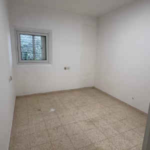 חדר ריק עם רצפת אריחים וקיר לבן