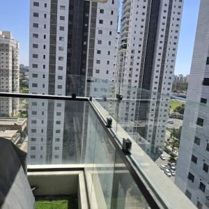 מרפסת עם מעקה זכוכית ונוף לבניינים גבוהים