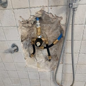 צנרת חשופה בקיר מקלחת עם ברזים וצינורות