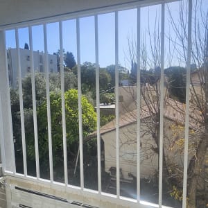 סורגים מותקנים על מרפסת עם נוף לעצים ובניינים