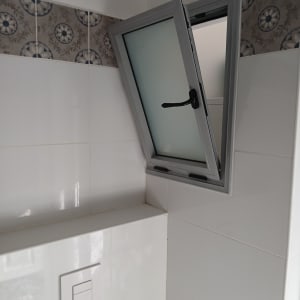 חלון אלומיניום פתוח עם ידית שחורה