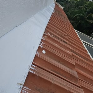 גג רעפים עם איטום לבן לאורך החיבור לקיר