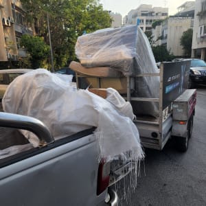 משאית עם רהיטים מכוסים בניילון ברחוב עירוני