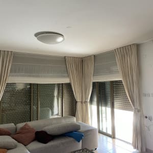 וילונות בהירים תלויים על חלונות גדולים בסלון