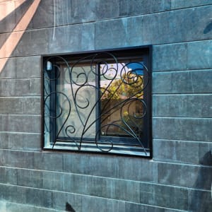 חלון עם מסגרת ברזל מעוצבת על קיר אבן אפור