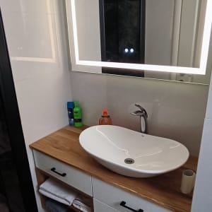 כיור לבן עם ברז על משטח עץ בחדר אמבטיה