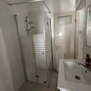 מקלחון זכוכית עם כיור וברז בחדר אמבטיה