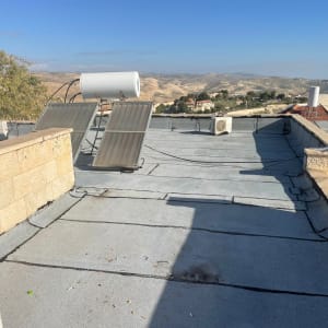 גג עם קולטי שמש ודוד מים, נוף הררי ברקע