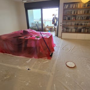 חדר עם רהיטים מכוסים בניילון, מברשת צבע על הרצפה