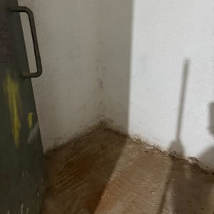 פינה ריקה עם דלת מתכת וצללים על הקיר