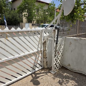 שער חשמלי לבן עם מנגנון פתיחה אוטומטי