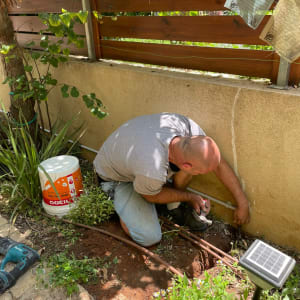 חשמלאי עובד עם צינורות וכלי עבודה בגינה