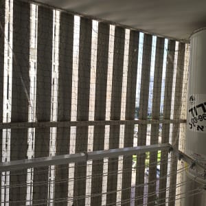 רשת יונים מותקנת על מרפסת עם דוד שמש