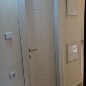 התקנת דלת פנים לבנה ומעוצבת עם חריצים אופקיים במסדרון