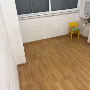 חדר ריק עם רצפת עץ, כיסא קטן וכיור