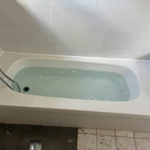 אמבטיה מלאה במים עם ברז ומקלחת יד