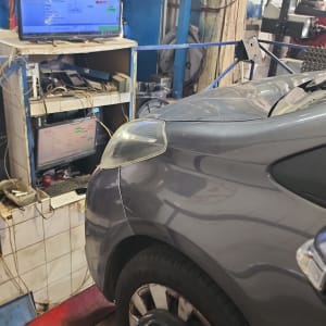 רכב במוסך עם ציוד בדיקה ומסך מחשב