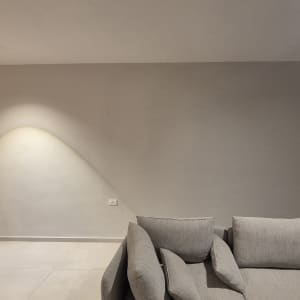 קיר צבוע עם תאורה וספה אפורה