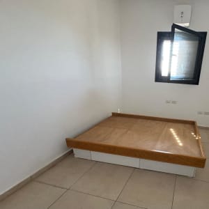 חדר ריק עם מיטה נמוכה ליד חלון פתוח